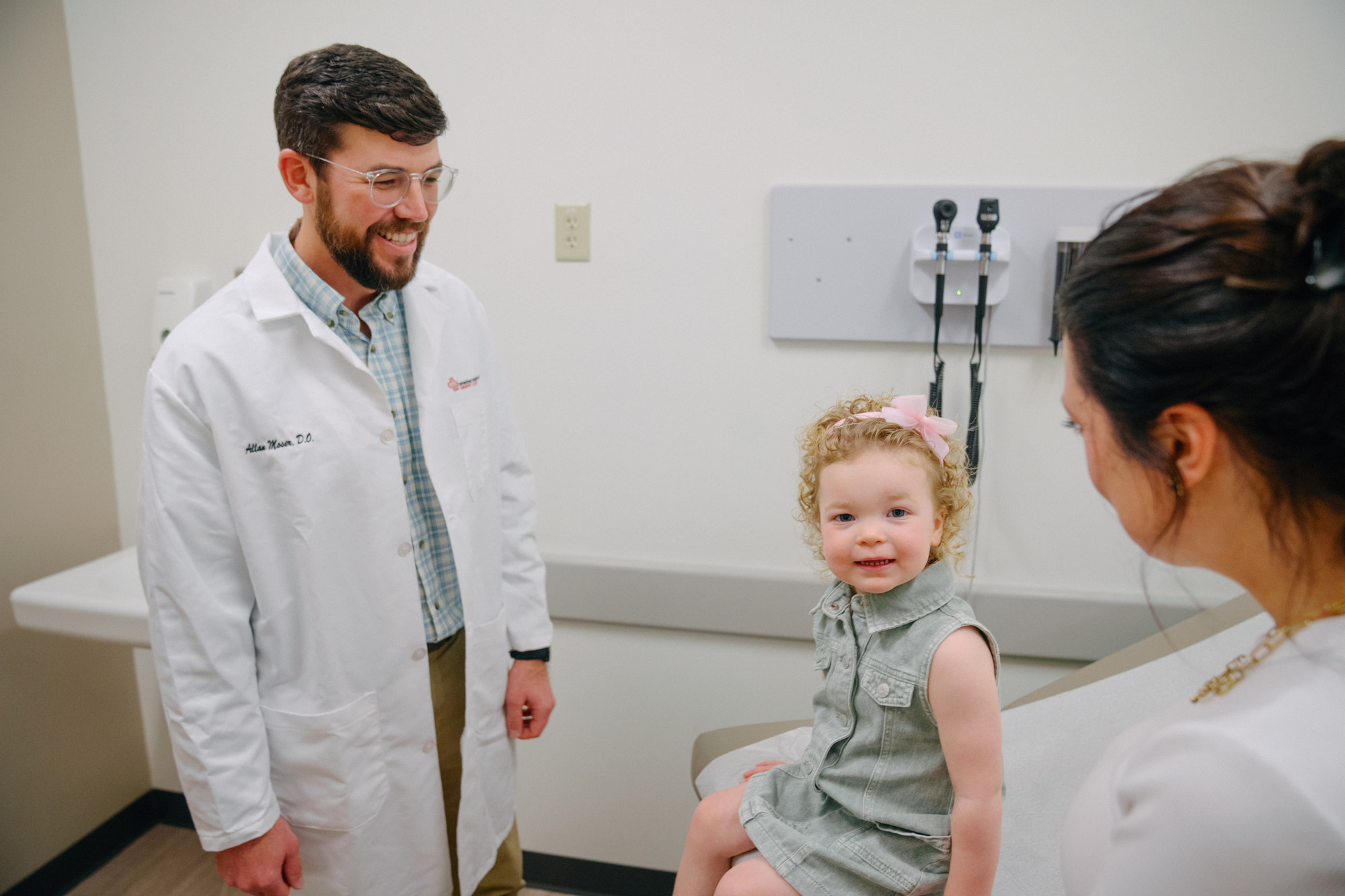 Healthcare provider smiles at young patient and parent.